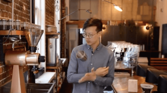 Swiss Water Video Education Series | Man in blue shirt standing in coffee shop tossing a cup into the air