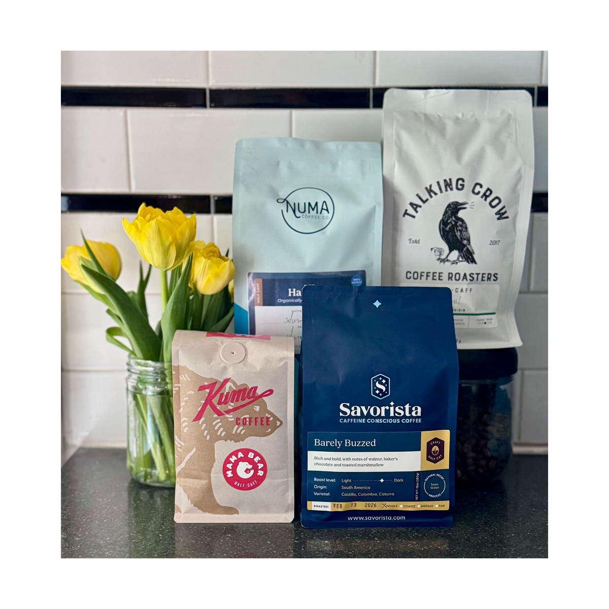 Half Caf Decaf Swiss Water Coffee Bags on a Kitchen Counter with Yellow Tulips