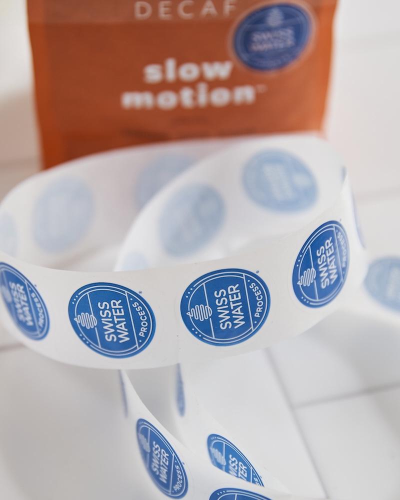 blue 'Swiss Water Process' labels on a blurred background of coffee packaging
