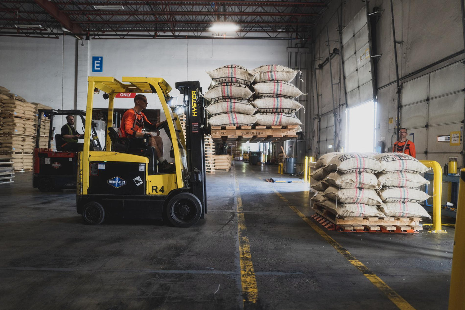Warehouse scene with forklifts and pallets of bags